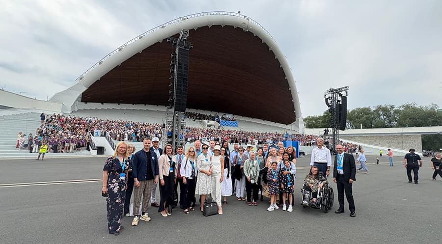 A group of people standing in front of a large audience at a concert venue.