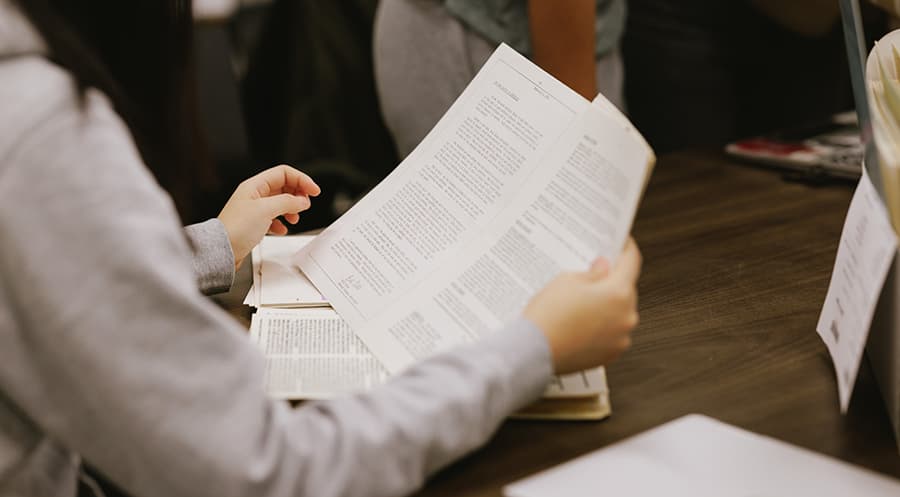 Close up of person reading papers at a desk.