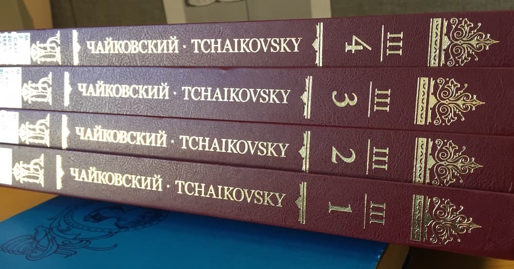 Four books with burgundy binding and gold colored lettering and markings on the spine on each score.