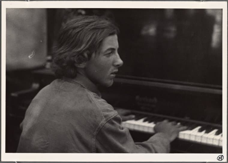 A black and white photo of young Henry Cowell seated at the piano